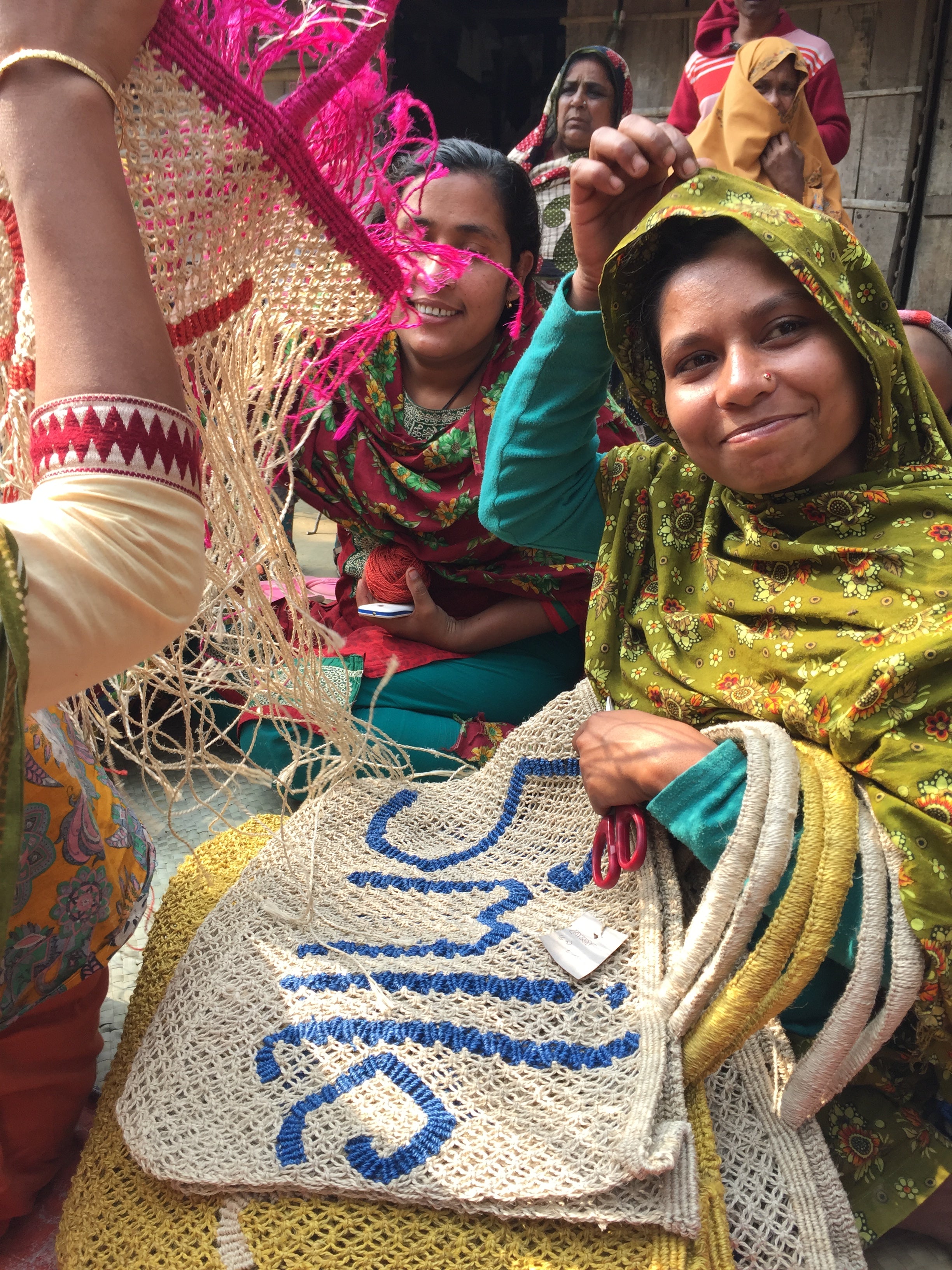 a group of women making jute bags outside