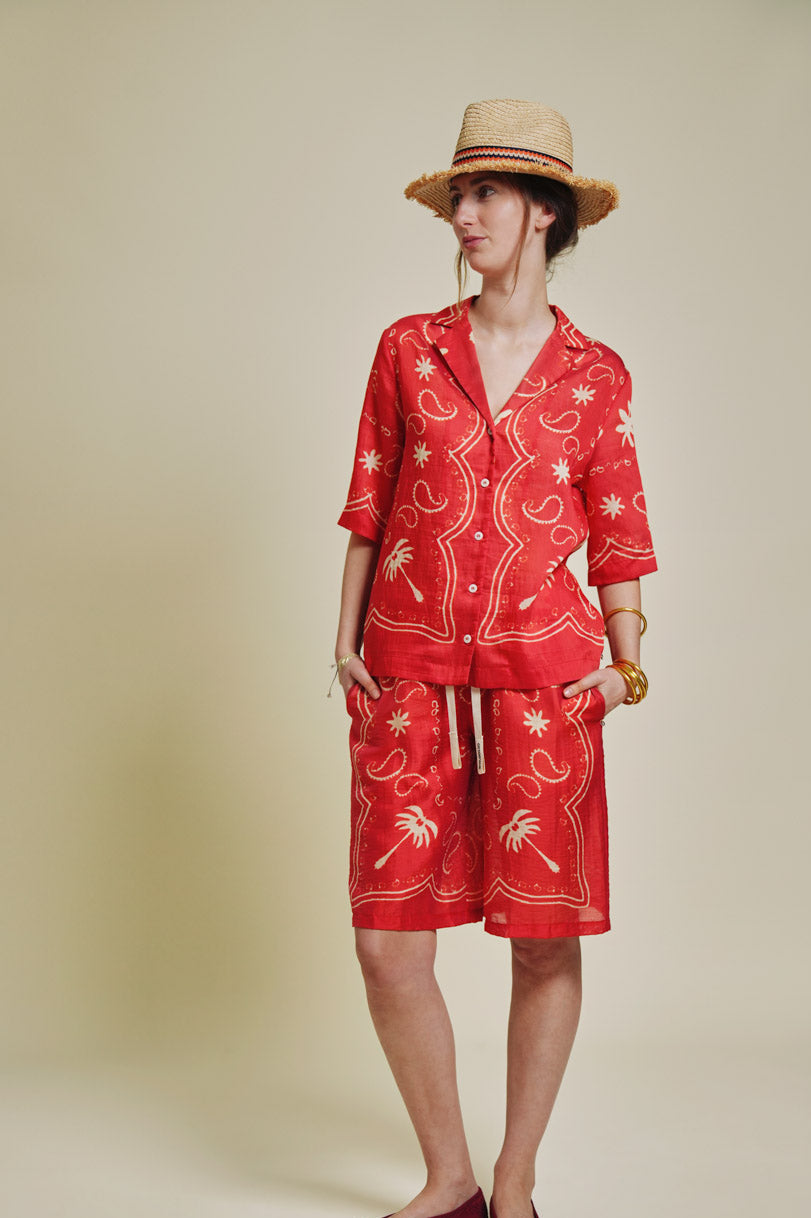 Person wearing a red outfit with palm tree patterns on a beige background