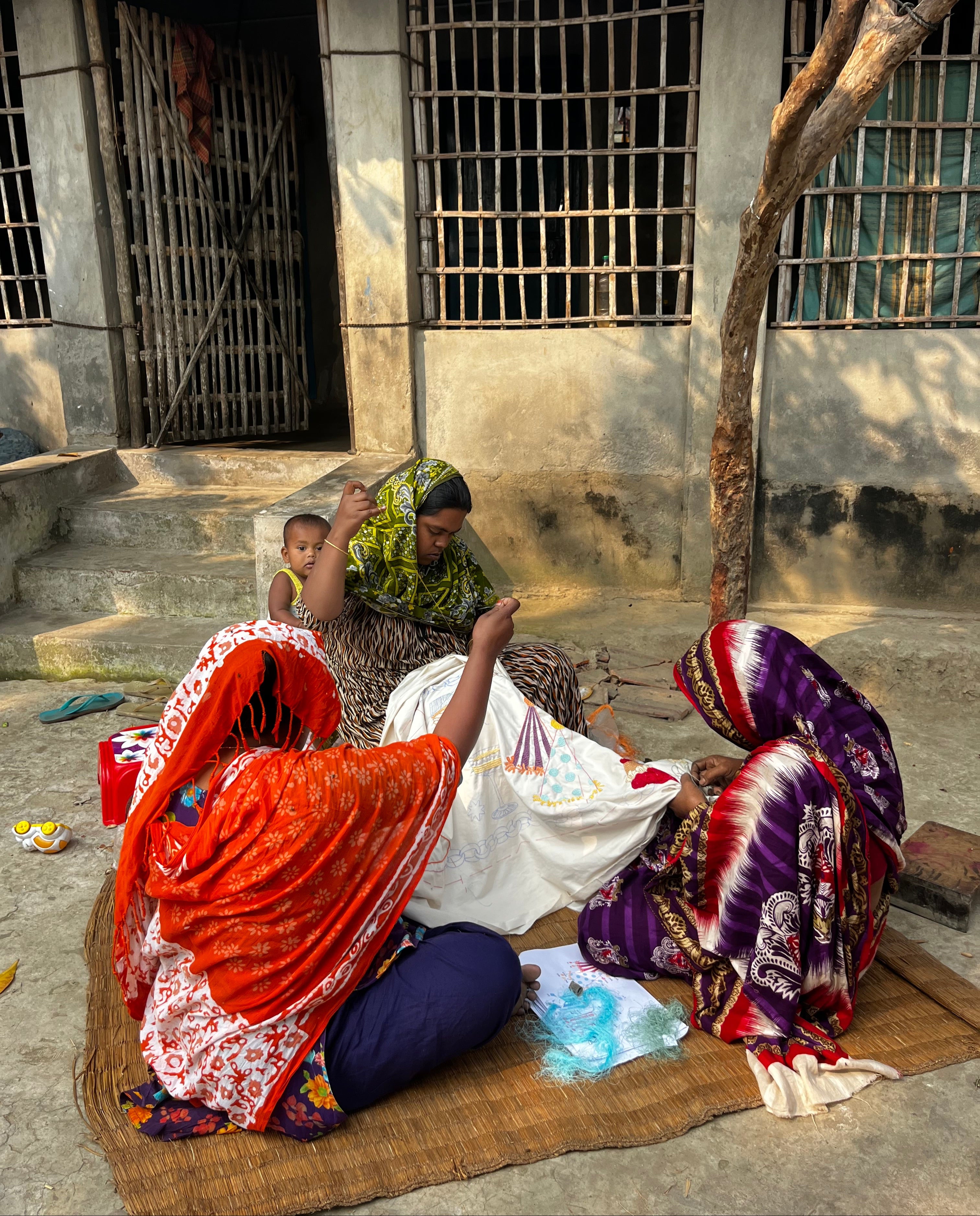 group of women working on embroidery in an outdoor setting