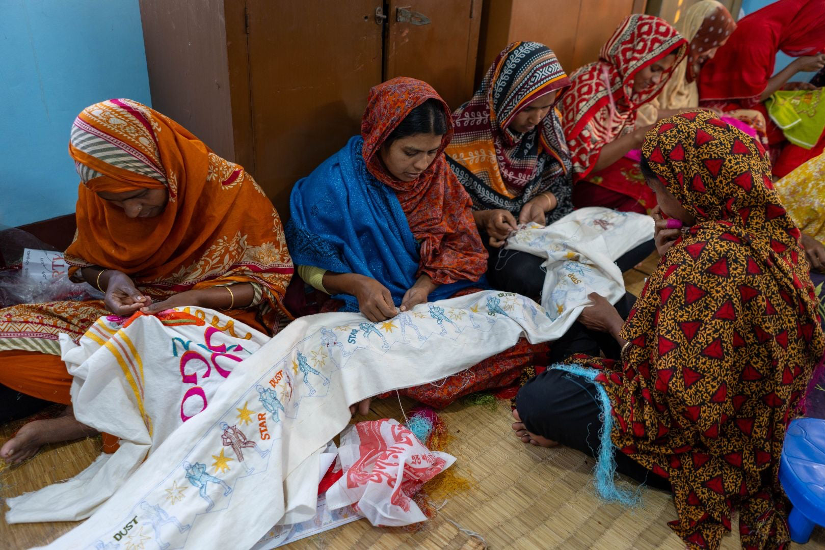 Group of women working on embroidery in a studio.