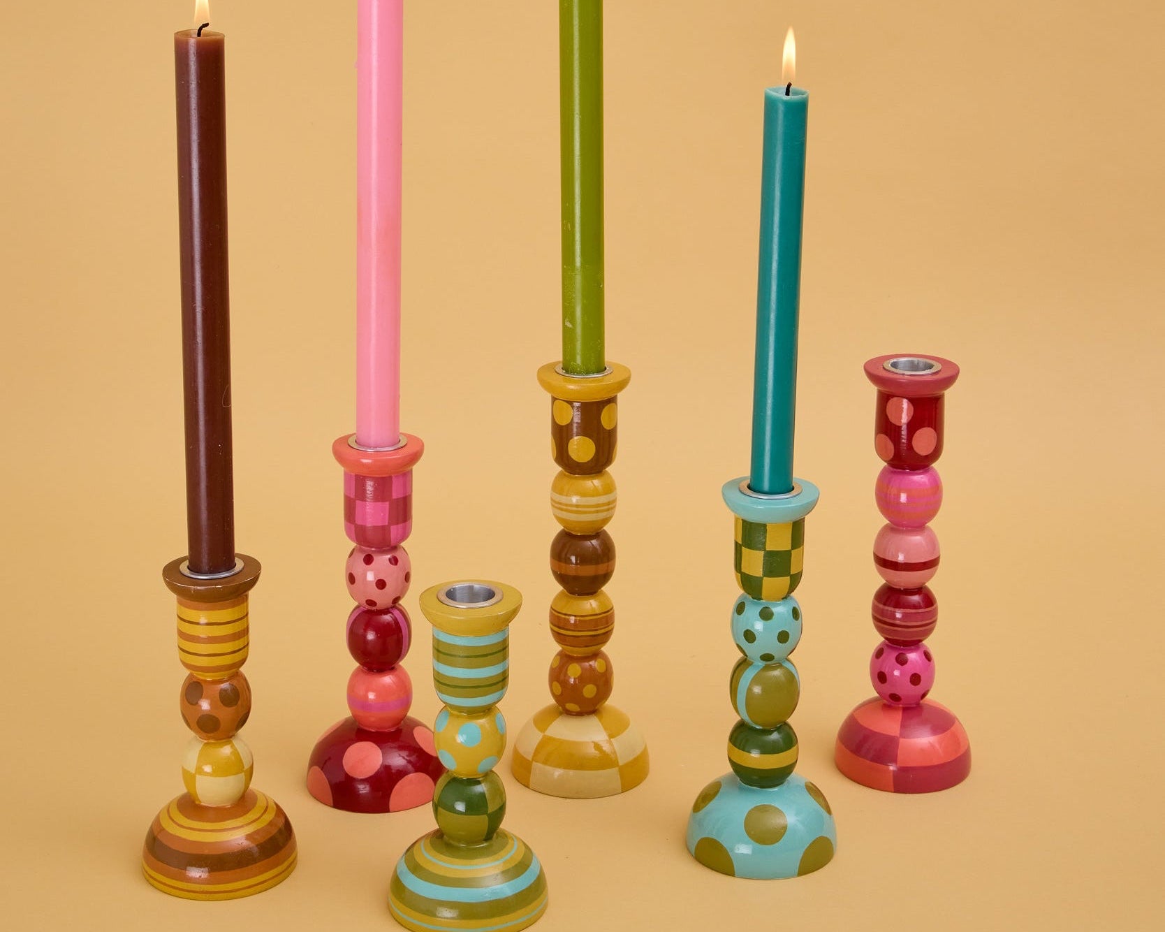 Colorful candle holders with candles on a beige background