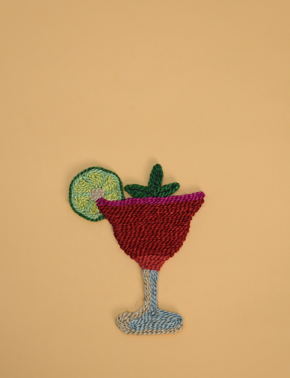 A colorful embroidered patch of a strawberry daiquiri, set against a solid beige background.