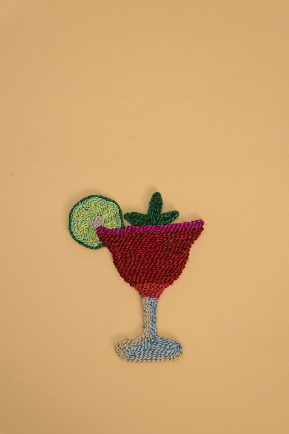 A colorful embroidered patch of a strawberry daiquiri, set against a solid beige background.